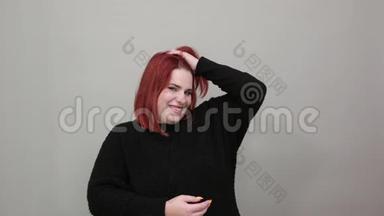 穿黑色毛衣的胖女人幸福的女人微笑着摸头，用手摸头发